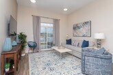 This thoughtfully designed 2-bedroom, 2-bathroom single-floor residence in Macon, GA offers a comfortable and stylish living experience. The open-concept kitchen serves as a central hub, featuring rich dark cabinetry, granite countertops, stainless steel appliances, a subway tile backsplash, open floating shelves, and a large island with seating for casual dining — all illuminated by pendant lighting overhead. The living area is bright and welcoming, with warm wood-look flooring, tall ceilings, and a sliding glass door framed by floor-length drapes that opens to an outdoor space with scenic views. The primary bedroom is a serene retreat, highlighted by a graceful upholstered headboard, matching nightstands, and a decorative sunburst mirror above the bed. It is accompanied by a walk-in closet and a private en-suite bathroom featuring granite counters, dark wood cabinetry, and a tub-shower combination. The second bedroom is equally well-appointed, boasting tall ceilings, a walk-in closet, and natural light from a generous window. Its adjacent bathroom mirrors the same refined finishes, including granite countertops and stylish pendant lighting. Throughout, neutral tones and warm wood flooring create a cohesive, inviting ambiance.