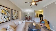 This well-appointed three-bedroom, two-bathroom single-story home in Indianapolis offers a thoughtfully designed layout with modern finishes throughout. Wood-look flooring flows through the main living areas, complementing the neutral gray tones that create a cohesive aesthetic across the space. The living room is a standout feature, anchored by a tiled fireplace and ceiling fan, with a sliding glass door that opens to an outdoor area and fills the room with natural light. Crown molding adds a refined touch to the living and dining areas. The kitchen is efficiently arranged with white cabinetry, granite-style countertops, and black appliances including a refrigerator, range, and microwave — all supported by ample counter and storage space. The adjacent dining area accommodates everyday meals with ease. The primary bedroom offers a comfortable retreat with a ceiling fan, natural light from a window with blinds, and plush carpeting. A secondary bedroom features direct bathroom access. Both bathrooms include tub/shower combinations, wood-look flooring, and white cabinetry. A dedicated in-unit laundry room with full-size washer and dryer hookups adds everyday convenience. Two closets and a hallway round out this practical and comfortable single-floor home.