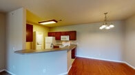 This single-floor residence is thoughtfully laid out to maximize functionality across its living spaces. The open-concept kitchen and living area forms the heart of the home, where rich cherry wood cabinetry pairs with neutral countertops and white appliances, including a refrigerator, electric range, microwave, and dishwasher. A peninsula with a built-in sink and overhang serves as both a prep station and casual dining area. A decorative chandelier anchors the dining zone, while the adjoining living area features warm hardwood flooring that transitions to plush carpeting. The living space includes a sliding glass door providing access to the outdoors and allowing natural light to filter in.

A dedicated laundry area is conveniently accessible directly from the kitchen. The bedrooms are carpeted and generously sized, with large windows that invite natural light and outdoor views. The bathrooms feature tile flooring, vanities with cherry wood cabinetry, and a tub-shower combination. Throughout the residence, a consistent warm neutral color palette and cohesive cabinetry finishes create a unified, functional aesthetic.