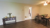 This single-floor space presents a straightforward and functional layout characterized by clean lines and a neutral color palette. The main living area features dark hardwood-style flooring that contrasts attractively with the warm beige walls, creating a grounded and cohesive aesthetic. A textured ceiling adds a subtle visual element to the room overhead.

The space is open and uncluttered, allowing for flexible furniture arrangements. A doorway connects the main area to an adjacent room, which appears to be a bathroom or utility space, featuring lighter flooring and offering a natural transition between areas. White door trim throughout provides a crisp contrast against the walls.

Baseboards run consistently along the perimeter, contributing to a finished appearance. The overall ambiance is calm and understated, making it a versatile backdrop suited to a variety of uses. Natural light filters into the connecting room, adding brightness to the interior. The space's simplicity and neutral tones make it adaptable for personalization through furnishings and décor.
