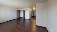 This efficiency unit offers a thoughtfully designed single-floor layout that maximizes functionality within a compact footprint. Rich, dark hardwood-style flooring runs consistently throughout the entire space, creating a cohesive and modern aesthetic. The kitchen is well-appointed with dark espresso cabinetry, granite-style countertops, a double-basin stainless steel sink, and a full suite of stainless steel appliances including a refrigerator, range, and built-in microwave. Ample upper and lower cabinet storage makes the kitchen both practical and visually striking. A hallway connects the kitchen to the main living area, where a stacked in-unit washer and dryer provide added convenience. The open living space is bright, featuring a large window that brings in natural light, along with a wall-mounted HVAC unit and baseboard heating. A closet with a hanging rod offers dedicated storage. The bathroom continues the dark cabinetry theme with a granite-topped vanity, a large mirror, and hardwood-style flooring. Grab bars are also present, adding an accessibility-conscious touch. The overall design is clean, modern, and functional throughout.