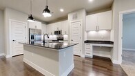 This 1,050 sq ft single-story home in Little Elm, TX features 2 bedrooms, 3 bathrooms, and 2 walk-in closets. The modern kitchen boasts white shaker cabinets, dark granite countertops, a large island with pendant lighting, subway tile backsplash, and stainless steel appliances, flowing seamlessly into the living area via hardwood flooring. Both bedrooms feature plush carpet and dual windows that invite natural light. The primary bath includes a double vanity with granite counters, backlit mirrors, and a soaking tub. Walk-in closets offer built-in shelving for ample storage.
