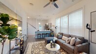 Located at 91 Bass Rd in Warner Robins, Georgia, this two-story home offers a thoughtfully designed layout that balances modern style with everyday functionality. The open-concept main level features a spacious living area bathed in natural light from large windows with blinds, complemented by a ceiling fan overhead and durable hardwood-style flooring throughout. The living space flows seamlessly into a well-appointed kitchen, which showcases gray shaker-style cabinetry, white quartz countertops, stainless steel appliances including a refrigerator, range, and microwave, and a generous island with bar seating illuminated by pendant lighting. A staircase connects the main level to the upper floor. The bedrooms are generously sized, featuring ceiling fans, hardwood-style flooring, natural light from windows, and walk-in closets for ample storage. The primary bedroom is a serene retreat with vaulted ceilings and peaceful natural light. The bathrooms are clean and functional, featuring tub-shower combinations and hardwood-style flooring. A dedicated laundry room with full-sized washer and dryer hookups and built-in shelving adds practical convenience. The home's neutral color palette and modern finishes create a bright, welcoming atmosphere throughout.