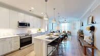 This well-appointed Lakewood, Colorado residence offers three bedrooms and three bathrooms across a single floor, thoughtfully designed with modern finishes and an efficient, open layout. The kitchen is a standout feature, showcasing white and light wood shaker cabinetry, a subway tile backsplash, stainless steel appliances, and a large central island with bar seating illuminated by pendant lighting — ideal for both cooking and casual dining. The kitchen flows seamlessly into the living room, which benefits from large windows that invite abundant natural light. A ceiling fan and direct access to the private balcony enhance the living area's comfort and connectivity to the outdoors. The primary bedroom features expansive windows with outdoor views and plush carpeting, creating a calm, restful retreat. Two additional bedrooms and two closets provide flexible storage and living options. The bathrooms are finished with clean white tile, light wood-tone flooring, and white quartz countertops, including a tub-shower combination. Wood-look plank flooring runs throughout the main living areas, while neutral-toned walls and hallways tie the space together with a cohesive, contemporary aesthetic.