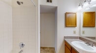 This single-floor unit at 6 N Lincoln Ridge Dr in Madison, WI offers a practical and comfortable layout with a range of functional features throughout. The living area is a standout space, highlighted by vaulted ceilings that lend a sense of openness and height. A ceiling fan complements the room, while a tile-surround fireplace with a white mantel serves as a focal point. A sliding glass door allows natural light to fill the space and provides access to an outdoor area. The kitchen is efficiently designed in a galley-style layout, featuring warm oak cabinetry, laminate countertops, tile flooring, and white appliances including a range, refrigerator, and over-the-range microwave. A pass-through connects the kitchen to the living area, enhancing the open feel. A walk-in closet or storage area is accessible from the kitchen. The bedroom is a well-proportioned, carpeted room with a large window that brings in natural light and views of surrounding greenery. The bathroom includes a vanity with oak cabinetry and laminate countertops, a wall-mounted medicine cabinet mirror, tile flooring, and a tiled tub and shower combination. Overall, the unit maintains a neutral, clean aesthetic throughout.