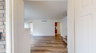This two-story home offers a practical and well-organized layout across two floors, accommodating four bedrooms and two full bathrooms. The main floor features a welcoming entrance that opens into a spacious living room, highlighted by light wood-style flooring, a ceiling fan, and a fireplace flanked by large windows fitted with vertical blinds that allow abundant natural light. The living room flows conveniently toward the kitchen, which is equipped with warm honey-toned wooden cabinetry, white countertops, a stainless steel sink, and black appliances including an electric range and dishwasher. A staircase with a railing leads to the upper floor, which houses the bedrooms. The generously sized primary bedroom offers comfortable proportions, while the additional bedrooms feature light flooring and bright, neutral walls. Bedrooms on the upper level include windows that allow natural light to filter in. The bathrooms are finished with wood-toned vanity cabinetry, white countertops, large wall mirrors, and wood-style flooring. Throughout the home, the clean white walls, neutral tones, and consistent flooring materials create a cohesive and bright atmosphere well-suited for everyday living.