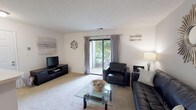 This single-floor residence offers a thoughtfully organized layout that balances comfort and functionality throughout its rooms. The living area serves as the heart of the home, finished with plush carpet and neutral walls that create a warm, inviting atmosphere. A sliding glass door floods the space with natural light and provides direct access to an outdoor patio, framing views of surrounding greenery. Decorative wall accents and a glass-top coffee table add character to the room.

The galley-style kitchen features cream cabinetry with wood-toned trim, light tile flooring, and a full suite of white appliances including a dishwasher, electric range, and built-in microwave. An in-unit laundry area is conveniently accessible directly from the kitchen.

The bedroom is a comfortable retreat, carpeted and naturally lit by a large window dressed with grey curtains. A ceiling fan with integrated lighting provides year-round climate comfort, while ample space accommodates substantial furniture including a full dresser and queen-sized bed.

The bathroom is finished with tile flooring, a tub-shower combination, a vanity with a light countertop, and clean, simple fixtures, completing this well-rounded residence.