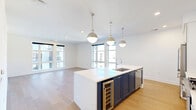 This thoughtfully designed 3-bedroom, 2-bathroom residence offers a seamless blend of modern aesthetics and functional living across a single floor. The open-concept kitchen and living area serves as the heart of the home, anchored by a striking navy blue island with a white quartz countertop, built-in wine refrigerator, and a stainless steel sink. Three globe pendant lights hang above the island, complementing the white shaker cabinetry, decorative tile backsplash, stainless steel appliances, and open shelving along the back wall. Light hardwood flooring extends throughout the main living areas, while large windows bathe the space in abundant natural light and provide views of the surrounding neighborhood. A clean, bright hallway connects the bedrooms, each carpeted for comfort. The generously sized primary bedroom features large windows and access to a luxurious en-suite bathroom outfitted with marble-look tile flooring, a dual-sink vanity with ample cabinetry, large mirrors, and a glass-enclosed walk-in shower with marble tile surround. Two closets provide excellent storage, including a spacious walk-in closet with built-in shelving and hanging rods. The additional bedrooms are well-proportioned, featuring ceiling fans and double-door closets. The overall aesthetic is crisp, contemporary, and move-in ready.