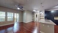 This 740 square foot apartment at Preserve at Gateway offers a thoughtful layout maximizing space and functionality. The single-floor design encompasses one bedroom, two full bathrooms, and an open-concept living area. The kitchen is a standout feature with dark wood cabinetry, stainless steel appliances, and a large center island with a granite countertop, perfect for meal preparation or casual dining.

The living room flows seamlessly from the kitchen, featuring rich hardwood flooring and access to a private balcony, bringing the outdoors in. The bedroom, measuring 150 square feet, boasts plush carpeting, a ceiling fan, and large windows that flood the space with natural light. 

Both bathrooms are well-appointed, with one featuring a combination tub/shower enclosure surrounded by neutral tiled walls. The unit also includes a spacious walk-in closet with wire shelving for ample storage. Throughout the apartment, recessed lighting and additional pendant fixtures provide excellent illumination.

The neutral color palette, consisting of warm beige walls and white trim, creates a versatile canvas for various decor styles. This apartment combines modern amenities with a practical layout, ideal for comfortable living in a compact space.