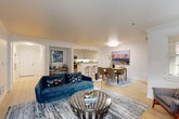 Located in Kirkland, WA, this well-appointed 2-bedroom, 2-bathroom residence offers a thoughtfully designed single-level floor plan with a clean, modern aesthetic. The open-concept living, dining, and kitchen area serves as the heart of the home, featuring light hardwood flooring, crown molding, and abundant natural light from large windows. The kitchen is equipped with white shaker cabinetry, granite countertops, stainless steel appliances, and a breakfast bar with seating, flowing seamlessly into the dining area and living room. An elegant arched hallway connects the main living area to the private quarters, adding a refined architectural touch. The generously sized primary bedroom is carpeted for comfort and includes mirrored closet doors, ample storage, and a serene atmosphere. A second bedroom offers similar comfort and versatility. The two bathrooms are well-appointed, with one featuring a glass-enclosed granite shower. Throughout the residence, five closets provide exceptional storage. Crown molding and clean white walls create a cohesive, polished look across every room, while the overall layout ensures a comfortable and functional living experience.