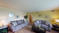 This single-floor residence offers a thoughtfully arranged layout with several distinct living areas. The living room is generously proportioned, featuring carpet flooring, crown molding, and neutral walls accented by chartreuse green panels that add a pop of color. Large windows fitted with horizontal blinds allow natural light to fill the space, offering outdoor views. The room comfortably accommodates multiple seating arrangements, making it ideal for relaxing or entertaining.

The dining area continues the green accent wall theme and features tile flooring, a window overlooking greenery, and a stylish pendant chandelier overhead, creating an inviting setting for meals.

The kitchen is outfitted with warm honey-toned cabinetry, ample counter space, a double sink, and tile flooring. A skylight adds brightness to the workspace.

The bedroom is carpeted and includes a ceiling fan with integrated lighting, a window with an outdoor view of surrounding greenery, and a closet with wood-panel doors, providing a calm, comfortable retreat.

The bathroom features a wood-framed mirror, a well-lit vanity with warm-toned cabinetry, a tub-shower combination, and coordinated navy accents.

A dedicated storage room with built-in shelving, tile flooring, and a fold-down work surface rounds out the space, offering practical organizational potential.