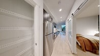 Located in Seattle's historic Pioneer Square neighborhood, this thoughtfully designed one-bedroom, one-bathroom residence offers a clean, modern aesthetic with warm, inviting touches throughout. Light wood-tone flooring runs continuously through the space, complementing the crisp white walls and recessed lighting that keep each room bright and airy.

The living room serves as the heart of the home, anchored by oversized windows that frame treetop and city views, flooding the space with natural light. The galley-style kitchen is efficiently appointed with gray shaker cabinetry extending to the ceiling, stainless steel appliances including a full-size refrigerator, gas range, dishwasher, and microwave, all set against a classic white subway tile backsplash with quartz countertops.

A long hallway connects the living areas to the private bedroom, which features a striking botanical-print accent wall that adds depth and character to the cozy retreat. A dedicated closet with built-in shelving provides organized storage. The bathroom is finished with a sleek floating vanity in gray, a white quartz countertop, large mirror, and in-unit laundry. A sliding barn door and clean architectural lines complete this well-planned, contemporary Seattle residence.