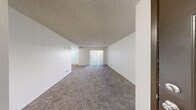 Located at 5055 East Charleston Boulevard in Las Vegas, NV, this single-story, one-bedroom, one-bathroom unit offers a functional and straightforward layout across a compact but efficient floor plan. The living room is a comfortable, open space featuring neutral-toned carpet, a textured ceiling, and vertical blinds covering a sliding door that allows natural light to filter in. Adjacent to the living area, the combined dining and kitchen space transitions to hard surface flooring and includes white cabinetry offering generous storage, a countertop with a single basin sink, and a white range, all arranged in a galley-style configuration. The bedroom is a well-proportioned private retreat with carpet flooring, a window dressed with vertical blinds, and access to a dedicated closet equipped with a hanging rod. The full bathroom features wood-look flooring, a single-sink vanity with cabinet storage, a toilet, and a tub-shower combination with a window providing natural ventilation. A hallway connects the rooms, contributing to an organized and practical flow throughout the unit. The clean, neutral palette and consistent use of natural light create a bright, livable atmosphere throughout.