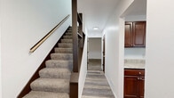Located at 1652 69th Ave NE in Fridley, Minnesota, this three-bedroom, two-bathroom home spans three floors, offering a well-organized layout suited for comfortable everyday living. The main level features a living room with carpeted flooring and a front entry door with a fan-light window, alongside a kitchen equipped with rich dark cherry cabinetry, granite-style countertops, wood-look vinyl plank flooring, and white appliances including a range and dishwasher. A dining area completes the main living space. Upstairs, three bedrooms provide carpeted comfort, including a generously sized primary bedroom. Dark-toned sliding closet doors and multiple closets throughout ensure abundant storage. Two full bathrooms serve the home, each with a tub-shower combination. The lower level includes a finished bonus room with wood-look flooring and an unfinished basement featuring a painted concrete floor, exposed ceiling joists, and a utility area housing mechanical systems — offering solid potential for future customization. Carpeted staircases with dark wood railings connect all three levels. A patio rounds out the exterior, providing outdoor space. The home's clean, neutral palette and consistent finishes create a move-in-ready environment throughout.