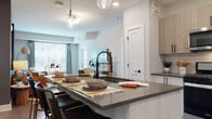 Located at 100 Union St in Elizabeth, NJ, this single-floor residence offers a thoughtfully designed layout with modern finishes and a vibrant, contemporary aesthetic. The open-concept kitchen is a standout feature, showcasing light wood cabinetry paired with crisp white lower cabinets, dark quartz countertops, a subway tile backsplash, and stainless steel appliances. A spacious island with seating and a matte black industrial-style faucet serves as both a functional workspace and a casual dining area, illuminated by elegant glass pendant lighting. The living area flows naturally from the kitchen, featuring large windows that invite abundant natural light, wood-style flooring, and ample space for comfortable furnishings. The bedrooms are generously proportioned, each offering plush carpeting, large windows with outdoor views, and ceiling fans. Accent walls in bold tones — deep teal and warm terracotta — lend each room a distinct character. The bathrooms are well-appointed with wood-toned vanities, dark quartz countertops, matte black hardware, and wood-style flooring. The full bath includes a tiled tub-shower combination, while the primary bath features a walk-in closet with built-in shelving. Throughout, the residence balances modern design with warm, livable touches.
