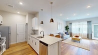 This well-designed one-bedroom, one-bathroom residence at 270 Main St in Sayreville, NJ offers a thoughtfully organized single-floor layout that maximizes functionality and style. The open-concept kitchen and living area serves as the heart of the home, anchored by a large central island with a quartz countertop, undermount sink, and seating for casual dining. The kitchen features white shaker cabinetry with matte black hardware, a subway tile backsplash, stainless steel appliances including a gas range and French door refrigerator, and stylish pendant lighting overhead. Warm hardwood flooring flows throughout the main living areas, contributing to a bright, cohesive aesthetic. The living room is generously sized, benefiting from large windows that invite natural light and provide outdoor views. The bedroom offers a comfortable footprint, plush carpeting, a walk-in closet with built-in shelving, and a window with sheer drapery for soft, diffused light. The bathroom is finished with large-format tile flooring, a grey shaker vanity with quartz countertop, matte black fixtures, a framed mirror, and a tiled tub-shower combination. Overall, the space presents a clean, modern ambiance throughout.