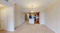 Located at 5960 Siegen Ln in Baton Rouge, Louisiana, this single-floor unit offers a well-designed, open layout that connects the living and kitchen areas seamlessly. The living space features neutral-toned carpet, crown molding, and built-in shelving, creating a clean and functional environment. A peninsula-style kitchen island serves as the focal point between the two spaces, accented by a pendant light overhead. The kitchen is fully equipped with warm oak cabinetry, black appliances including a refrigerator, range, microwave, and dishwasher, and light countertops. Track lighting and hardwood-style flooring complete the kitchen's practical aesthetic. The bedrooms are carpeted and generously sized, each benefiting from soft natural light. The primary bedroom connects directly to a well-appointed en-suite bathroom featuring dual vanities with rich wood cabinetry, a soaking tub with tile surround, and hardwood-style flooring. A large walk-in closet with wire shelving provides ample storage. A secondary bedroom with carpet and a ceiling fan offers comfortable additional living space. Throughout the unit, a neutral color palette and consistent finishes contribute to a cohesive and move-in-ready atmosphere.