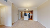 Located at 5960 Siegen Ln in Baton Rouge, Louisiana, this single-floor unit offers a well-designed, open layout that connects the living and kitchen areas seamlessly. The living space features neutral-toned carpet, crown molding, and built-in shelving, creating a clean and functional environment. A peninsula-style kitchen island serves as the focal point between the two spaces, accented by a pendant light overhead. The kitchen is fully equipped with warm oak cabinetry, black appliances including a refrigerator, range, microwave, and dishwasher, and light countertops. Track lighting and hardwood-style flooring complete the kitchen's practical aesthetic. The bedrooms are carpeted and generously sized, each benefiting from soft natural light. The primary bedroom connects directly to a well-appointed en-suite bathroom featuring dual vanities with rich wood cabinetry, a soaking tub with tile surround, and hardwood-style flooring. A large walk-in closet with wire shelving provides ample storage. A secondary bedroom with carpet and a ceiling fan offers comfortable additional living space. Throughout the unit, a neutral color palette and consistent finishes contribute to a cohesive and move-in-ready atmosphere.
