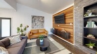 Located in Arlington, Washington, this single-story community amenity space is thoughtfully designed to offer residents a well-rounded environment for relaxation, socializing, and fitness. The interior blends contemporary design elements with warm, inviting accents throughout.

The entry area greets visitors with large-format tile flooring, a bold chartreuse accent wall, pendant lighting, and a convenient coffee station. A glass-paneled door leads into the main lounge, where rich hardwood-style flooring and curated furnishings create a comfortable gathering space. A striking floor-to-ceiling stacked stone fireplace wall serves as the room's focal point, flanked by built-in shelving and complemented by plush velvet accent chairs. Adjacent to the fireplace, a horizontal wood-paneled wall showcases a mounted flat-screen television above floating media storage.

The kitchen is outfitted with stainless steel appliances, dual-tone cabinetry featuring white uppers and dark wood lowers, light quartz countertops, and a vibrant yellow hexagonal tile backsplash that ties into the space's energetic color palette. A bright nook with multiple windows and garden views provides an inviting spot for small meetings or casual dining.

The expansive fitness center features blue sport flooring, large wall mirrors, cardio equipment including a treadmill and rowing machine, a cable weight system, TRX suspension trainer, adjustable bench, and free weights, offering a comprehensive workout facility.