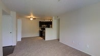Located at 5400 Diamond Loch in Columbus, Ohio, this single-floor unit offers a practical and well-appointed living space with a cohesive design throughout. The open-concept living area is finished with neutral wall-to-wall carpeting, a textured ceiling, and a ceiling fan with integrated lighting, creating a comfortable and airy atmosphere. A half-wall partition separates the living area from the kitchen, maintaining an open sightline while defining each space. The kitchen is a standout feature, designed as a galley-style layout with dark espresso cabinetry that contrasts sharply against light countertops. A mosaic tile backsplash in earth tones adds a stylish, contemporary touch. The kitchen is equipped with black and stainless steel appliances, including a range, refrigerator, and overhead microwave. A stainless steel sink is positioned beneath upper cabinetry, and pendant lighting overhead adds a modern accent. Light hardwood-style flooring runs throughout the kitchen, complementing the overall aesthetic. The space combines functional design with updated finishes, making it a well-suited home for everyday living in Columbus's west side.