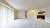 Located at 1108 Kennebec St. in Oxon Hill, Maryland, this single-floor residence offers a well-organized and comfortable layout designed for everyday living. The expansive living area is finished with plush wall-to-wall carpeting and neutral warm-toned walls that create a bright, open atmosphere. Large vertical blinds along a wide window allow generous natural light to fill the space, while a ceiling fan adds both function and character. The living area flows seamlessly into a secondary carpeted space, offering flexibility for dining or additional seating arrangements. The kitchen is thoughtfully appointed with rich dark wood cabinetry, granite-style countertops, a subway tile backsplash, wood-look flooring, and black appliances including a gas range — providing an efficient and stylish cooking environment. The bedrooms feature soft carpeting, neutral walls, and ample closet space, including what appears to be a walk-in closet in the primary bedroom. The bathroom showcases a clean, modern aesthetic with floor-to-ceiling stone-look tile surrounding a white soaking tub, lending a spa-like quality to the space. Throughout the residence, consistent neutral tones and well-maintained finishes contribute to a calm, move-in-ready ambiance.