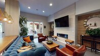 Located at 1947 NW Overton St in Portland, Oregon, this single-floor space offers a thoughtfully designed open-concept layout that seamlessly blends contemporary style with comfortable, functional living. The living area serves as the centerpiece of the space, anchored by a striking floor-to-ceiling tile accent wall that houses a wall-mounted flat-screen TV above a sleek linear electric fireplace. Rich leather armchairs, a tufted blue velvet sofa, and a solid wood coffee table create an inviting and well-curated seating arrangement. A reclaimed wood accent wall adds warmth and texture to the adjacent area, complemented by a decorative sunburst mirror. Recessed lighting and a mini-split HVAC unit provide comfort throughout. The kitchen is efficiently laid out with stainless steel appliances including a full-size refrigerator, range with overhead hood, and dishwasher, along with wood-toned cabinetry and dark countertops. Open shelving adds a modern touch. A long wooden dining table with bar-height stools sits beneath a trio of striking geometric gold pendant lights, bridging the kitchen and living areas. French doors open directly to a covered outdoor patio, allowing natural light to fill the interior and providing a smooth indoor-outdoor connection. The consistent large-format tile flooring throughout ties the space together with a clean, modern aesthetic.