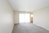 This single-floor residential unit offers a practical and comfortable layout with a variety of well-appointed spaces. The galley-style kitchen is efficiently designed, featuring white cabinetry with black hardware, ample upper and lower storage, a coil-burner electric range, a built-in dishwasher, and durable wood-look plank flooring. A hallway connects the kitchen directly to the bathroom, enhancing the flow of the space.

The living area is generously sized, finished with neutral-toned carpet and a textured ceiling. A large sliding glass door fitted with vertical blinds floods the room with natural light and provides outdoor views, creating an open and airy atmosphere. Adjacent rooms offer additional flexible living or sleeping space, each carpeted and featuring windows with blinds that allow for natural light while maintaining privacy.

The bedrooms are well-proportioned, with multiple windows in the primary room offering cross-ventilation and bright natural light. One bedroom includes access to a closet area, adding to its functionality.

The bathroom is clean and streamlined, with wood-look tile flooring, a single-sink vanity with white cabinetry, a wall-mounted mirror, and a tiled shower/tub surround. The neutral color palette and consistent finishes throughout the unit create a cohesive and welcoming ambiance.