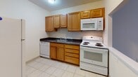 Located at 75 Gardner St in the Allston neighborhood of Boston, MA, this single-floor unit offers a practical and well-organized layout. The living area is bright and open, featuring warm hardwood flooring that flows throughout the main spaces, neutral cream-toned walls, and windows that allow natural light to filter in. Baseboard heating units are present along the exterior walls, ensuring comfortable warmth throughout the colder months.

The kitchen is efficiently designed with warm-toned wood cabinetry, dark granite-style countertops, white tile flooring, and a classic white tile backsplash. It is equipped with a full suite of appliances including an electric range, over-the-range microwave, and dishwasher, offering solid functionality for everyday cooking.

The bedroom mirrors the aesthetic of the main living area, with hardwood floors, neutral walls, a window with natural light, and baseboard heating. The bathroom is clean and straightforward, finished with light tile flooring and white wall tiles, and includes a full shower-tub combination.

The overall layout, as shown in the dollhouse view, connects the living room, kitchen, bedroom, and bathroom in a compact and accessible flow. The space offers a clean, move-in-ready environment well-suited for urban living in Boston.