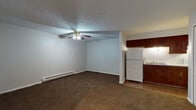 Located at 1802 Trinity Place NW in Canton, Ohio, this single-floor unit offers a practical and functional layout suited for comfortable everyday living. The open living area is finished with wall-to-wall carpeting and features a ceiling fan with integrated lighting, a textured ceiling, and baseboard heating along the perimeter walls. The space flows directly into the kitchen, which is equipped with rich, dark-toned wood cabinetry both above and below the counters, a double-basin stainless steel sink, white electric coil range, and a full-size refrigerator. Tile flooring grounds the kitchen area, providing a clear visual transition from the carpeted living space.

The bedroom is generously sized, also finished with carpet, and includes a full-width closet fitted with louvered bifold doors and a metal hanging rod. Light-toned walls throughout the unit contribute to a bright and neutral interior atmosphere.

The bathroom features a vanity with dark wood cabinetry, a marble-patterned countertop, a mirrored medicine cabinet, and a full tub and shower combination with white tile surround. Tile flooring completes the bathroom. Overall, the unit presents a clean, functional layout with consistent finishes throughout.