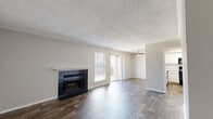 This single-floor, 2-bedroom, 1-bathroom home offers a functional and cohesive layout throughout. Dark wood-look flooring runs consistently across all rooms, providing a warm, unified aesthetic complemented by neutral gray walls and white trim.

The living room serves as the centerpiece of the home, featuring a black tile fireplace, crown molding, a textured ceiling, and a ceiling fan. A sliding glass door allows natural light to fill the space and provides outdoor access. The adjacent dining area continues the open feel with crown molding and ample room for a full dining set.

The kitchen is well-appointed with white shaker-style cabinetry, stone-look countertops, a subway tile backsplash, a double basin sink, a dishwasher, and an electric range. A window above the sink brings in natural light and outdoor views.

Both bedrooms are comfortably sized, with the primary bedroom offering generous square footage and natural light from a window. The second bedroom is similarly bright and well-proportioned.

The full bathroom features a white vanity with a stone-look countertop, a tub-shower combination with white tile surround, and wood-look flooring. A dedicated laundry room with shelving accommodates a full-sized washer and dryer. A hallway and closet complete the practical layout of this well-designed home.