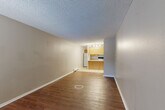 Located at 7545 Bradburn Blvd in Westminster, CO, this two-bedroom, one-bathroom single-floor unit offers a practical and efficiently organized layout. The open-concept living, dining, and kitchen area serves as the heart of the home, featuring warm hardwood-style flooring throughout and a textured ceiling. The kitchen is equipped with light wood cabinetry, a peninsula with a built-in sink and countertop space, a range, and a full-size refrigerator, all finished with tile flooring. Natural light enters through a window in the living area, which also includes a wall-mounted A/C unit and baseboard heating. A connecting hallway leads to the two bedrooms, both carpeted and featuring closets — one with a sliding door and one with an open rod-and-shelf system. The primary bedroom benefits from a window with natural light and baseboard heating. The shared bathroom is finished with tile flooring, a wood-framed vanity with a speckled countertop, a large mirror, and a tub/shower combination with built-in shelving. A grab bar is also present, adding accessibility. Two additional closets provide ample storage throughout the unit.