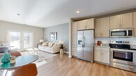 Located at 1331 Crossings Blvd in Shakopee, MN, this one-bedroom, one-bathroom residence offers a well-designed single-floor layout that maximizes functionality and comfort. The open-concept living and kitchen area forms the heart of the home, finished with warm wood-look luxury vinyl plank flooring throughout. The kitchen is outfitted with light maple cabinetry extending to the ceiling for ample storage, granite countertops, a classic white subway tile backsplash, and a full suite of stainless steel appliances including a side-by-side refrigerator with water dispenser, range, microwave, and dishwasher. The living room flows naturally from the kitchen and receives generous natural light through large French doors that open to an outdoor view, creating a bright and welcoming atmosphere. The bedroom features plush carpeting, multiple windows that invite natural light, and direct access to a spacious walk-in closet outfitted with multi-level wire shelving and hanging rods for organized storage. The bathroom continues the clean, neutral palette with wood-look flooring and a vanity with ample counter space. Neutral gray tones, recessed lighting, and clean white trim throughout lend the space a modern, cohesive aesthetic.