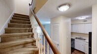 Located at 3940 Macon Rd in Columbus, Georgia, this two-story home offers three bedrooms, two bathrooms, and a practical layout spread across two well-proportioned floors. The main level features hardwood-style flooring throughout the living areas, a pendant-lit dining or living space with warm neutral walls, and a compact kitchen equipped with white cabinetry, a dishwasher, range, and a full-size refrigerator. A louvered-door closet and a full bathroom with a vanity, mirror, and tub round out the first floor. A carpeted staircase with a classic wood banister and white spindles connects the two levels, adding a traditional architectural touch. The upper floor houses the bedrooms, each finished with plush carpeting, ceiling fans with light fixtures, and windows that allow natural light to filter in. The spacious primary bedroom offers room for comfortable furnishings. A second bathroom on this level features a granite-topped vanity, updated fixtures, and hardwood-style flooring. Two closets provide dedicated storage throughout the home. The textured ceilings and neutral color palette create a clean, versatile interior ready for personalization.
