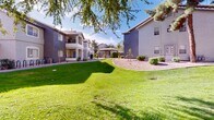 Located at 1155 W Grove Pkwy in Tempe, Arizona, this multi-building residential complex offers a well-designed outdoor environment that blends functional layout with comfortable communal living. The complex consists of several three-story stucco buildings finished in neutral gray and taupe tones, characteristic of Southwestern architectural style, with tiled rooflines and private balconies on upper levels.

The grounds are a standout feature, showcasing expansive, well-manicured green lawns interspersed with mature shade trees that provide natural relief from the Arizona sun. Curved concrete walkways wind through the landscaped courtyard areas, connecting the various buildings and creating a cohesive, pedestrian-friendly environment. Desert-adapted gravel beds and low-maintenance shrubs border building foundations, blending Arizona xeriscaping principles with lush turf areas.

Each building entrance is clearly marked with unit numbers and accessed via open-air stairwells with metal railings, providing straightforward access to all floor levels. Covered parking structures are visible within the complex, offering residents convenient protected parking. Pet-friendly amenities, including waste stations, are thoughtfully integrated into the grounds. The overall ambiance is open, airy, and inviting, with abundant natural light throughout the exterior spaces and a relaxed residential atmosphere well-suited to the Tempe climate.
