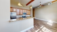 This 710 square foot apartment efficiently utilizes space to offer comfort and style. The heart of the home is a modern kitchen, featuring light wood cabinetry, stainless steel appliances, and elegant granite countertops. The open-concept design seamlessly connects the kitchen to the living area, which boasts high ceilings with exposed wooden beams, creating an airy and spacious atmosphere.

The single bedroom, measuring 140 square feet, provides a cozy retreat. It features a striking exposed brick wall, adding character and texture to the space. The bathroom is well-appointed with a granite-topped vanity, a combination tub and shower, and the added convenience of in-unit laundry facilities.

Throughout the apartment, wood-look flooring adds warmth and continuity. The hallway connects the various spaces efficiently, while a closet offers additional storage. Large windows allow natural light to flood the space, enhancing the open feel of this compact yet thoughtfully designed urban dwelling.