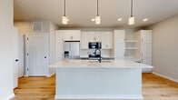 This 620-square-foot, one-bedroom, one-bathroom residence at 1211 Carrington Blvd in Mount Pleasant, WI offers a modern and efficiently designed single-floor layout. The open-concept kitchen is a standout feature, boasting a large white quartz island with an undermount sink and matte black fixtures, white shaker cabinetry with black hardware, stainless steel appliances including a French door refrigerator with ice maker, electric range, and built-in microwave, complemented by light hardwood flooring and pendant lighting. The living area is bright and airy, featuring a glass-paneled front entry door with transom windows that flood the space with natural light. The primary bedroom spans 160 square feet, offering plush neutral carpeting, a large window with exterior views, a walk-in closet with built-in shelving, and convenient access to an in-unit stacked washer and dryer. The bathroom features a full tub-shower combo with built-in shelving, crisp white surrounds, light hardwood flooring, and sleek matte black hardware and accessories. The unit's clean, neutral palette and contemporary finishes throughout create a cohesive and move-in-ready living environment.