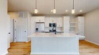 This 620-square-foot, one-bedroom, one-bathroom residence at 1211 Carrington Blvd in Mount Pleasant, WI offers a modern and efficiently designed single-floor layout. The open-concept kitchen is a standout feature, boasting a large white quartz island with an undermount sink and matte black fixtures, white shaker cabinetry with black hardware, stainless steel appliances including a French door refrigerator with ice maker, electric range, and built-in microwave, complemented by light hardwood flooring and pendant lighting. The living area is bright and airy, featuring a glass-paneled front entry door with transom windows that flood the space with natural light. The primary bedroom spans 160 square feet, offering plush neutral carpeting, a large window with exterior views, a walk-in closet with built-in shelving, and convenient access to an in-unit stacked washer and dryer. The bathroom features a full tub-shower combo with built-in shelving, crisp white surrounds, light hardwood flooring, and sleek matte black hardware and accessories. The unit's clean, neutral palette and contemporary finishes throughout create a cohesive and move-in-ready living environment.