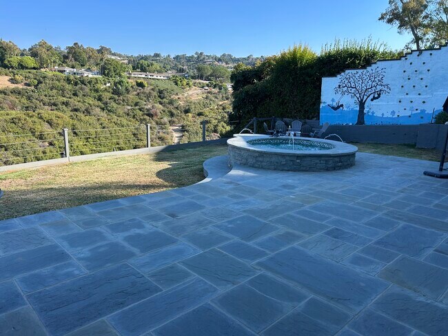 Patio trasero con piedra azul, fuente/jacuzzi empotrado y pared de escalada. - 27078 Sunnyridge Rd