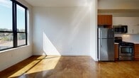 Located at 54 Beale St in Quincy, Massachusetts, this single-floor unit offers a thoughtfully designed layout with a consistent modern aesthetic throughout. The space is distinguished by its polished, stained concrete floors, which flow seamlessly from room to room, providing a sleek and durable foundation that adds both character and visual warmth.

The open living area benefits from ample natural light, with sunlight casting across the concrete floors and bright white walls, creating an airy and welcoming atmosphere. A pass-through window connects one room to another, adding an architectural detail that enhances the sense of openness while maintaining defined areas within the layout.

The kitchen is well-appointed with stainless steel appliances, including a gas range, over-the-range microwave, refrigerator, and dishwasher. A combination of warm wood cabinetry and white upper cabinets provides practical storage, while light countertops offer a clean, contemporary workspace.

The bathroom continues the unit's modern design language, featuring a soaking tub with shower, a wall-mounted storage cabinet, and a clean white vanity, all set against the same polished concrete flooring found throughout the rest of the space. The overall ambiance is minimal, functional, and contemporary.