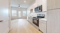 Located at 5900 S Congress Ave in Austin, TX, this thoughtfully designed two-bedroom, two-bathroom unit offers a bright and modern living experience on a single floor. The open-concept layout seamlessly connects the kitchen, dining, and living areas into one cohesive space. The kitchen is well-appointed with stainless steel appliances—including a range, over-the-range microwave, dishwasher, and refrigerator—complemented by white subway tile backsplash, white upper cabinetry, light wood-tone lower cabinets, and clean white countertops. A ceiling fan overhead and double doors leading to an outdoor area enhance the living space with added airflow and natural light. Light wood-tone flooring runs throughout the entire unit, creating a warm and consistent aesthetic. Both bedrooms are generously windowed with horizontal blinds, offering ample natural light and a neutral palette ready for personalization. The primary bedroom provides direct access to its own bathroom. Both bathrooms feature light wood-tone cabinetry, white countertops, soaking tubs with tiled surrounds, and framed mirrors. Additional practical spaces include a laundry area, utility room, hallway, and three closets, ensuring functional storage throughout the unit.