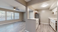 Located at 21215 Detroit Rd in Rocky River, OH, this well-appointed 2-bedroom, 2-bathroom single-floor home offers a thoughtfully designed layout with modern updates throughout. The open living room serves as the heart of the home, highlighted by a classic brick fireplace with a decorative iron screen, a ceiling fan with light fixture, recessed lighting, and durable wood-look LVP flooring. A bank of windows along the exterior wall fills the space with natural light and offers views of the surrounding greenery. The kitchen flows seamlessly from the living area and features white cabinetry, a stainless steel refrigerator, a peninsula with a light-toned countertop, and matching LVP flooring, creating a cohesive and functional space. Both bedrooms are carpeted and neutral in tone, offering comfortable, quiet retreats. One bedroom includes a closet and a window with natural light. The two bathrooms are finished with marble-look tile throughout. The first features a tub-shower combination with large-format tile surround and brushed nickel fixtures, while the second offers a tiled walk-in shower, a white vanity, and a mirrored medicine cabinet. A connecting hallway links the private areas of the home efficiently. The overall palette of warm grays and whites gives this home a clean, contemporary feel.