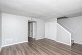 Located at 1057 Cherryfield Run in Marietta, Georgia, this two-story home offers a well-organized layout across two levels. The main floor features durable hardwood-style flooring throughout the living and dining areas, complemented by neutral-toned walls and textured ceilings that add character to the space. A carpeted staircase with a louvered closet nearby connects the main level to the upper floor. The kitchen is thoughtfully appointed with white cabinetry, marble-style countertops, a gray tile backsplash, stainless steel appliances including an electric range and dishwasher, and a double basin sink beneath a window that brings in natural light. The bedrooms feature plush wall-to-wall carpeting and ceiling fans, with windows fitted with horizontal blinds offering privacy and light control. Additional rooms with hardwood-style flooring provide flexible living space. The bathroom includes a vanity with white cabinetry and a tub-shower combination with richly toned stone-style tile surround. Throughout the home, clean white trim, consistent neutral paint tones, and ample natural light from multiple windows create a bright and cohesive living environment suited for comfortable everyday living.