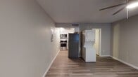 This single-floor studio in Phoenix, AZ offers a practical and efficiently designed layout that maximizes its open living space. Wood-look laminate flooring runs throughout, providing a cohesive and clean aesthetic across all areas of the unit.

The main living area is open and versatile, featuring a ceiling fan with integrated lighting and a window that allows natural light to fill the space. Neutral gray walls create a calm, modern backdrop, while clean white baseboards add a polished finish. An electrical panel is conveniently housed within the unit.

The kitchen is a standout feature, outfitted with stainless steel appliances including a range, over-the-range microwave, and a full-size refrigerator. White cabinetry, light quartz-style countertops, and a classic white subway tile backsplash give the kitchen a crisp, updated look. A stacked washer and dryer unit is located just adjacent to the kitchen, offering convenient in-unit laundry.

A hallway connects to a bathroom featuring a vanity with drawer storage, and leads to an additional room with its own window, providing natural light and added flexibility. The textured ceiling is consistent throughout the unit, complementing the overall understated design.
