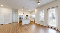 Located in Jacksonville, FL, this single-story home offers a thoughtfully designed layout across three bedrooms, two bathrooms, and a dedicated laundry room. The open-concept kitchen and living area serves as the heart of the home, featuring warm wood-look flooring, recessed lighting, and a ceiling fan overhead. The kitchen is outfitted with crisp white cabinetry, granite countertops, stainless steel appliances including a refrigerator with ice maker, electric range, microwave, and dishwasher, as well as a central island with pendant lighting. Natural light flows in through multiple windows, some with views of the exterior. The bedrooms offer a comfortable retreat, with the primary bedroom providing generous proportions and a walk-in closet with wire shelving. Secondary bedrooms feature plush carpet and access to additional closets. The bathrooms are finished with wood-look flooring, and one includes a subway-tiled tub and shower combination with a window for natural light. Outside, the home is part of a community with manicured lawns and black iron fencing. The exterior showcases white lap siding and a traditional roofline.