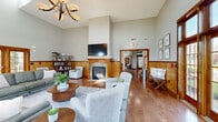 Located at 1 Ascot Cir in Saratoga Springs, NY, this generously sized single-floor clubhouse blends classic craftsmanship with comfortable, versatile gathering spaces. The welcoming entrance greets visitors with striking slate tile flooring, soaring ceilings, and warm wood-framed French doors that flood the space with natural light from multiple directions. Rich wood wainscoting runs throughout, providing a consistent design thread that ties each room together.

The main living areas are expansive and airy, with dramatic vaulted ceilings accented by skylights, hardwood flooring, and a handsome wood-mantled fireplace as a central focal point. Large multi-pane windows and glass doors offer views of the surrounding greenery, enhancing the bright and open ambiance. Multiple seating arrangements throughout the living rooms accommodate both intimate gatherings and larger groups with ease.

A dedicated home theater room features tiered leather recliner seating and a projection screen, offering a premium entertainment experience. The billiards room, adorned with horse racing artwork nodding to the area's Saratoga heritage, includes a full-size pool table beneath a classic pendant light. Hallways connect each area fluidly, ensuring smooth circulation throughout the layout. The overall atmosphere is warm, inviting, and thoughtfully designed for community use.