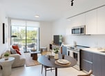 This contemporary 580 square foot apartment in Miami Gardens showcases a thoughtful blend of style and functionality. The open-concept layout maximizes the use of space, creating a seamless flow between the living areas. The living room is bathed in natural light from large windows, complemented by a sliding glass door leading to a private balcony with verdant views.

The kitchen boasts a sleek design with two-tone cabinetry, stainless steel appliances, and a convenient dining area. Modern track lighting and recessed fixtures provide ample illumination throughout. The bedroom features a minimalist aesthetic with monochromatic tones and artistic wall prints, while the bathroom offers a clean, spa-like ambiance with a large vanity and glass-enclosed shower.

Neutral color palettes dominate the space, accented by pops of color in the form of throw pillows and artwork. The apartment's cohesive design elements, including consistent flooring and trim, create a harmonious living environment. Despite its compact size, the clever layout and design choices make this apartment feel spacious and inviting, perfect for modern urban living.