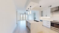 Located at 180 Patriots Point Rd in Mount Pleasant, South Carolina, this thoughtfully designed 2-bedroom, 4-bathroom residence offers a refined single-level layout with modern finishes throughout. Light-toned hardwood-style flooring flows seamlessly across every room, complemented by crisp white walls and black hardware accents that define the contemporary aesthetic.

The open-concept kitchen and living area serves as the heart of the home. The kitchen is anchored by a striking waterfall-edge quartz island with an undermount black sink and pendant lighting above. White shaker-style cabinetry reaches toward the ceiling, paired with a stainless steel appliance suite, a wine cooler, and under-cabinet lighting. French doors in the living area invite natural light and provide outdoor access.

The generously sized primary bedroom features dual windows with outdoor views, a ceiling fan, and access to a well-appointed walk-in closet with custom shelving and black hanging rods. The four bathrooms are finished with clean tile work and matte black fixtures, including a tub-shower combination with a handheld showerhead.

A dedicated laundry room houses a front-loading GE washer and dryer beneath a quartz folding counter with overhead shelving. Two hallways connect the layout efficiently, and two closets provide ample storage throughout this polished, move-in-ready residence.