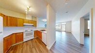 Located at 431 NW 100th Pl in Seattle, WA, this 2-bedroom, 2-bathroom residence offers a well-designed, single-floor layout with a clean, neutral aesthetic throughout. Light wood-style flooring flows seamlessly across all rooms, creating a cohesive and bright atmosphere.

The open living room is generously sized, bathed in natural light from large windows and a glass door that leads to a private balcony with outdoor views of the surrounding neighborhood. The kitchen sits adjacent to the living area, featuring warm honey-toned wood cabinetry, white appliances including a refrigerator, electric range, and dishwasher, a double sink, and a pass-through counter that connects to the main living space.

The spacious primary bedroom offers a large closet with double panel doors and a bright window framing outdoor greenery. The second bedroom is also well-proportioned and includes a window with natural light and a baseboard heater. Each bedroom is served by its own bathroom — one featuring a wide vanity with warm wood cabinetry and an extended mirror, the other with a walk-in shower, single vanity, and matching wood cabinetry. A hallway and closet complete the layout, providing practical storage and smooth circulation throughout the home.