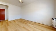 Located at 919 S Manhattan Pl in the Mid-City neighborhood of Los Angeles, CA, this efficiently designed single-floor unit offers a thoughtful layout across a cozy footprint. Light hardwood flooring runs consistently throughout the space, creating a warm and cohesive aesthetic from room to room.

The living area is bright and open, featuring white walls, a ceiling fan with light fixture, and a double window that invites natural light while offering views of the surrounding neighborhood. A wall-mounted heating unit and a window air conditioning unit ensure year-round comfort.

The kitchen is compact and functional, equipped with a white gas range with overhead ventilation hood, a tile-topped counter, and a sink — providing the essentials for everyday meal preparation in an efficient space.

The bathroom continues the light and clean aesthetic with wood-look tile flooring, a toilet, and a standalone shower enclosed by a frosted glass door with a chrome frame. A towel bar adds a practical finishing touch.

The entrance provides a clean transition into the unit, setting the tone for the simple, neutral interior throughout. The overall design palette — white walls, light floors, and chrome accents — gives the space a fresh, move-in-ready feel suitable for urban living in Los Angeles.