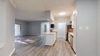 Located in the Chenal Valley area of Little Rock, Arkansas, this single-floor residence offers a clean, modern aesthetic with a cohesive design throughout. The open-concept layout connects the living and dining areas to the kitchen, creating a spacious and functional flow. Cool gray walls and light wood-look vinyl flooring are consistent throughout the home, lending a fresh, contemporary feel.

The kitchen is well-appointed with white shaker-style cabinetry, white countertops, a stainless steel sink with a modern gooseneck faucet, a dishwasher, refrigerator, and electric range. A center island provides additional workspace and a natural divider between the kitchen and the living area. A pass-through counter further enhances the open feel.

The living area is generously sized, bathed in natural light, and features sliding glass doors that open to an outdoor space with views of surrounding trees. Multiple bedrooms offer ample natural light through large windows with blinds, and include closets with built-in shelving. Two full bathrooms are finished with white cabinetry, white countertops, tiled tub-shower combinations, and matching wood-look flooring. The overall design is clean, neutral, and move-in ready.